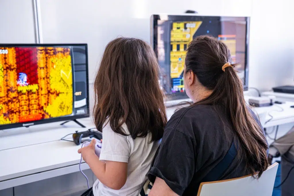 Mère et fille jouant à des jeux rétros au stand La Chronique du Geek à la 404CONFOUND